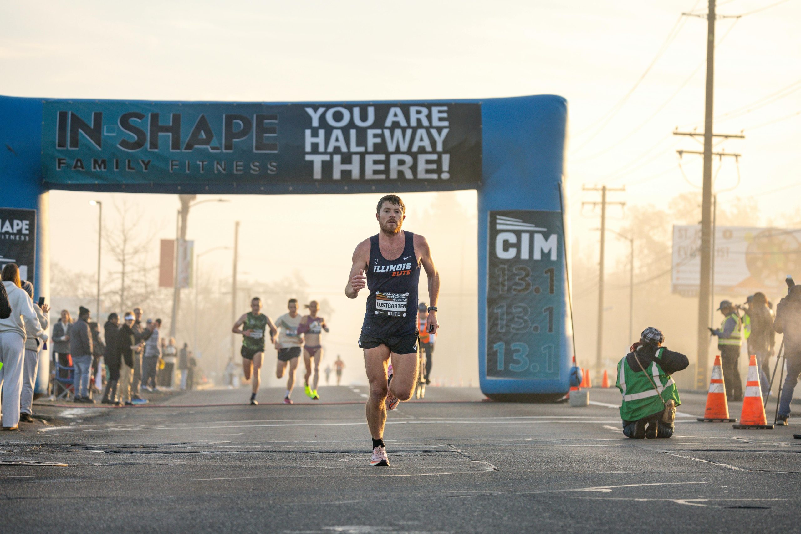 Runner approaching the halfway mark in a marathon event with spectators and photographers capturing the moment.