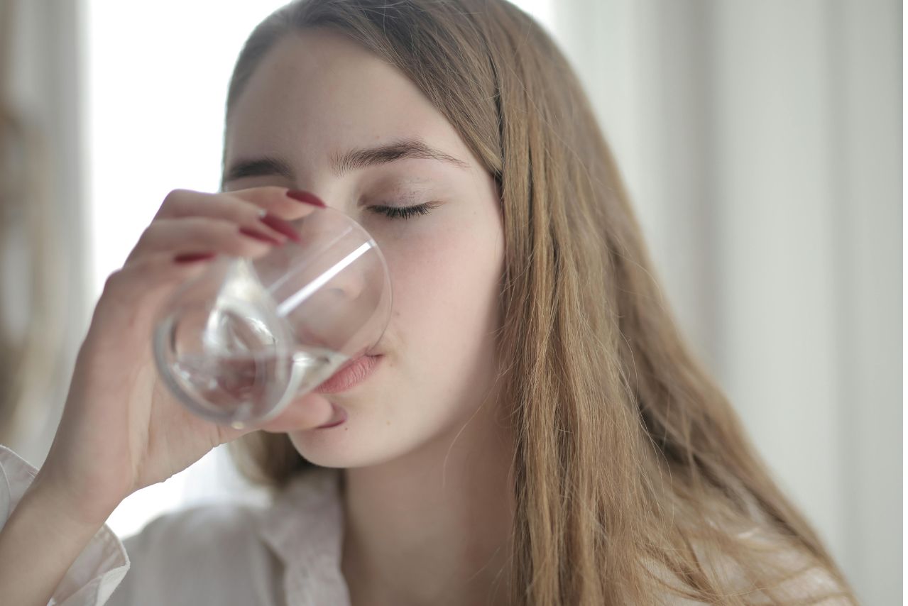 Woman in White Shirt Drinking Water From Clear Glass with Her Eyes Closed
